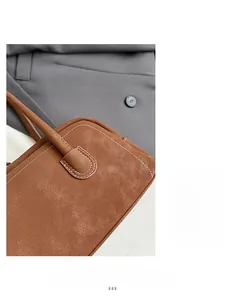Detailed close-up of brown textured leather bag with white stitching on gray fabric background