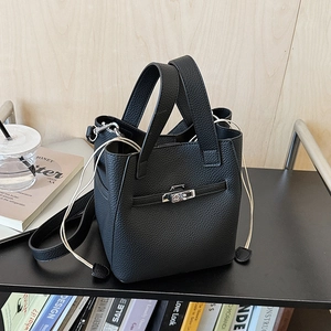 Detail of black lychee grain leather bucket bag with silver twist lock and drawstring