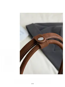 Detail of brown leather handle with lychee texture and silver metal buckle on boston bag
