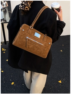 Close-up of brown suede shoulder bag featuring silver rivets and stylish long tassels