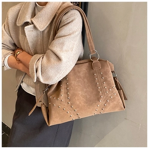Detailed close-up of brown tote bag with silver rivet studs and textured matte finish
