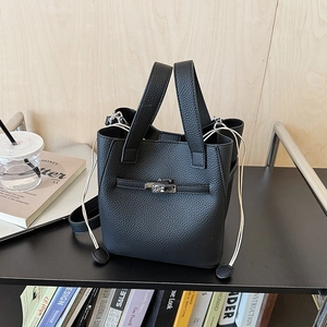 Detail view of black lychee leather bucket bag with silver clasp and cream drawstrings