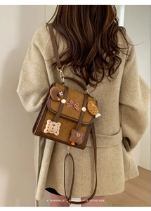Detailed view of vintage brown backpack with cute cookie plushies and checkered bow