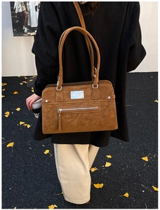 Detailed view of brown suede tote bag with silver zippers and long shoulder straps