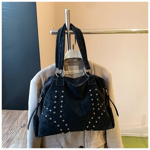Détail du sac cabas en daim noir avec rivets dorés et grands anneaux métalliques
