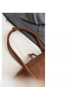 Detail of brown litchi pattern leather strap and double zipper closure on hobo bag