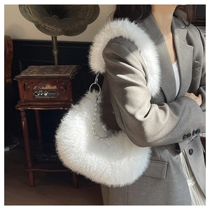 Détail du sac en peluche blanche avec bandoulière en perles porté sur un tailleur gris