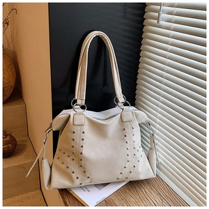 Vue détaillée du sac cabas beige avec clous argentés sur surface en cuir souple
