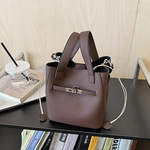 Detailed view of deep brown pebbled leather bucket bag with silver turn-lock and cream drawstrings
