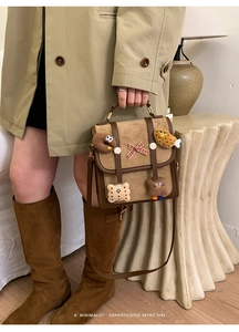 Detailed shot of retro brown handbag with cartoon charms and a plaid bow decoration