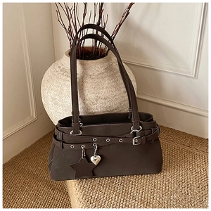 Detail of dark brown leather Boston bag featuring star charm and buckle belt aesthetics