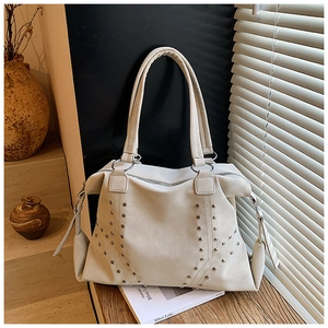 Détail du sac fourre-tout blanc crème avec rivets argentés sur fond de bois texturé