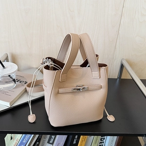 Detail view of beige leather bucket bag with silver twist lock and drawstring closure