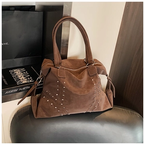 Détail du sac cabas en daim marron foncé avec clous argentés et double poignée