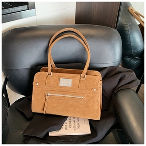 Close-up of brown vintage shoulder bag with matte leather texture and metal tag detail