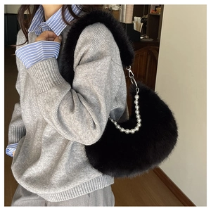 Détail du sac sous le bras en fausse fourrure noire avec chaîne perlée et fermoir argent
