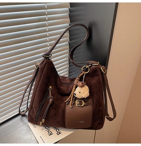 Detail of retro large capacity brown suede shoulder bag with plush pendant and fringe