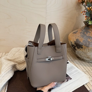 Detailed macro shot of the taupe pebble leather texture and silver buckle on bucket bag