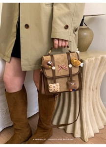 Detail of retro brown suede handbag with cute plush cartoon patches and plaid bow