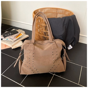 Détail d'un sac cabas kaki avec rivets métalliques en V et texture en cuir mat