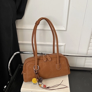 Dettaglio borsa Boston in pelle marrone con cuciture a contrasto e ciondolo boho