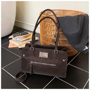 Detail of matte retro coffee shoulder bag featuring metal logo and textured finish