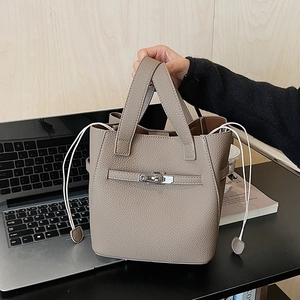Close-up of elephant gray lychee grain leather bucket bag with metallic lock detail