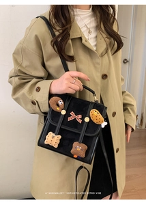 Detail of vintage black bag with plush bread patches and a red checkered bow