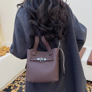 Close-up of a dark brown lychee leather bucket bag featuring a silver metal twist lock