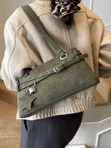 Dark green suede Boston bag with silver star and heart charms worn as a shoulder bag