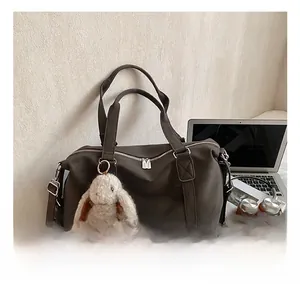 Detail der dunkelbraunen Totebag mit Plüschhasen-Anhänger neben Laptop und Kopfhörern