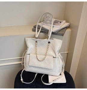 Detail of white quilted patent leather tote bag with metal chain and side drawstring