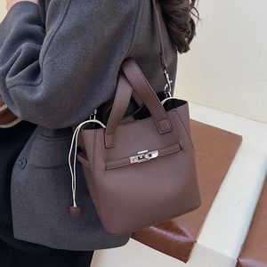 Detail of dark brown lychee grain leather bucket bag with metallic twist lock and strap