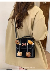 Detail of retro black leather bag with cute cartoon dessert patches and a red bow knot