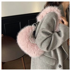 Sac croissant en peluche rose avec chaîne en perles porté avec un manteau gris