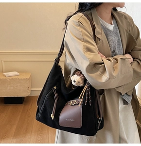 Detail of hobo tote bag in black suede and brown leather with cute bear charm decoration