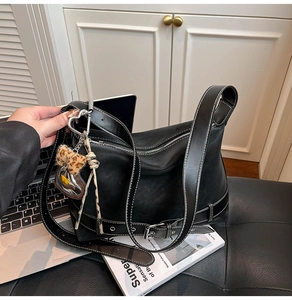 Detail of black faux leather tote with white contrast stitching and heart leopard charms