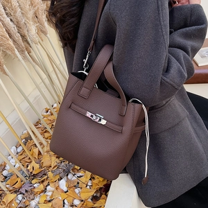 Detail of dark brown pebble leather bucket bag with metal lock in an autumn setting