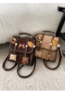 Detail of vintage suede backpacks in brown and khaki with cute plush cookie charms