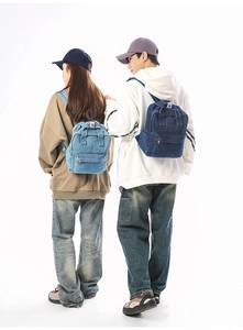 Detailansicht hellblauer und dunkelblauer Denim-Rucksäcke getragen von Models im Studio