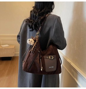 Detail of vintage brown suede tote bag with a metal buckle and plush puppy charm