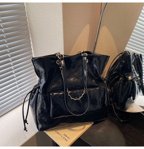 Detailed view of black quilted patent leather bag with a gold-tone chain and drawstring