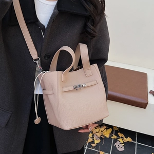 Detail view of pink lychee grain leather bucket bag with silver twist lock and strap