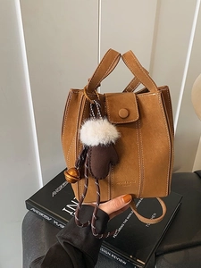 Brown suede minimalist bucket handbag with decorative glove charm and metal bell detail