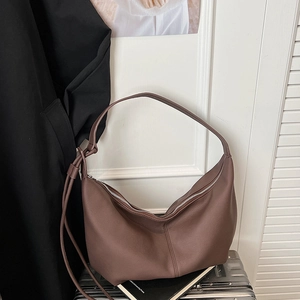 Close-up of dark brown leather tote bag with soft lychee texture on silver suitcase