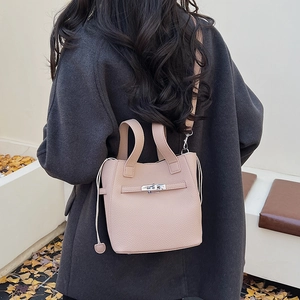 Detail view of pink lychee leather bucket bag featuring a silver metal twist lock buckle