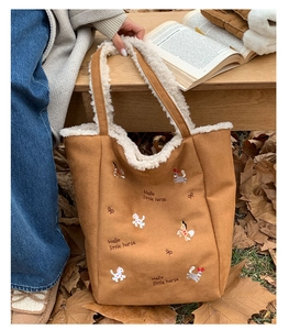 Dettaglio della borsa in pelle scamosciata marrone con bordo in lana e ricamo a cavallo