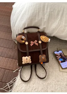 Detail of vintage brown suede backpack with cute plush biscuit pendants and bow