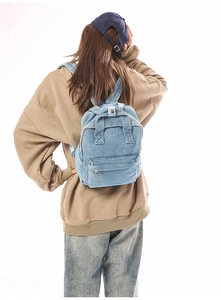 Gewaschener Denim Rucksack am Modell zeigt lässigen Retro-Stil und Trägerdetails