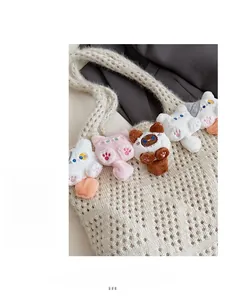 Detail of cream crochet tote bag featuring cute plush cat dolls and woven texture